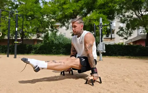 Un homme musclé exécute un exercice de calisthenics, jambes tendues, dans un parc. Un entraînement complet pour un corps athlétique.