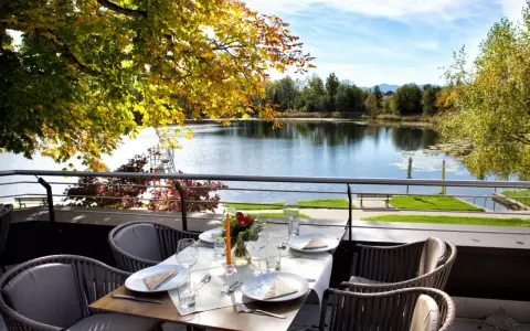 Gedeckter Tisch mit Blick auf einen See und Herbstlaub.