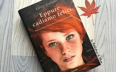 Copertina del libro "Eppure cadiamo felici" di Enrico Galiano, con il volto di una ragazza dai capelli rossi e occhi azzurri. Una foglia d'acero rossa completa la scena.