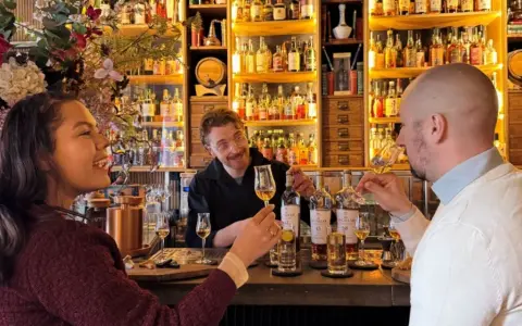 Två personer njuter av en ölprovning i Stockholm. En glad bartender serverar.