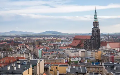 Widok na miasto z dominującą wieżą katedry. W oddali góry. Odkryj **Świdnica atrakcje**!