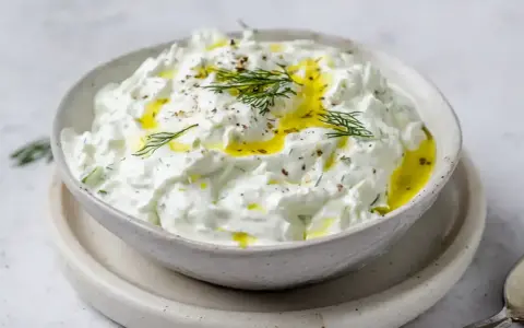 En skål med krämig tzatziki, perfekt för ditt tzatziki recept. Toppad med olivolja och färsk dill.