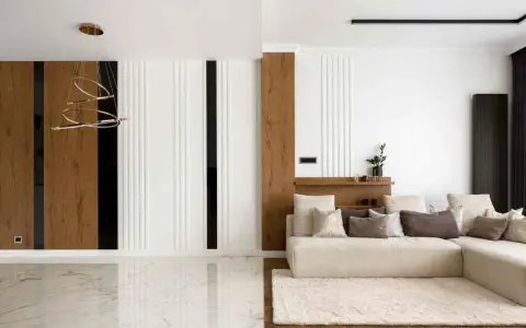 Interni di una casa minimalista con divano beige, tappeto soffice e lampadario moderno. Pareti con pannelli in legno e finiture bianche.