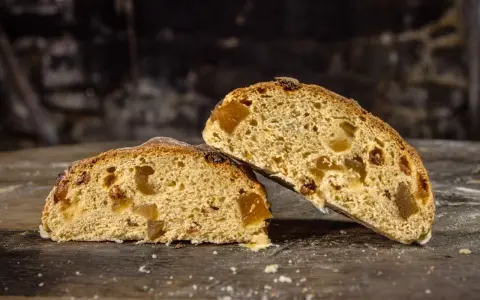 Deux tranches de pain au levain de gingembre, garnies de fruits confits, sur une table en bois rustique.