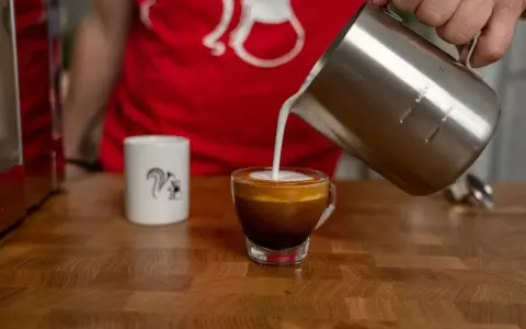 Milchschaum fließt in einen Espresso, um einen perfekten Espresso Macchiato zu kreieren.