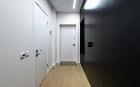 Paredes blancas y negras contrastan en este pasillo largo y estrecho, con puertas y armarios modernos.