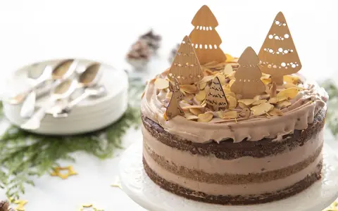 Gâteau au chocolat décoré d'arbres de Noël en bois, d'amandes effilées et d'un lapin.