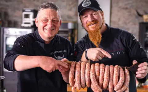 Zwei Metzger präsentieren stolz eine Reihe von frisch gefüllten Salsiccia mit Haut, bereit zum Braten.