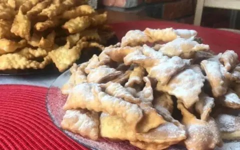 Stos puszystych faworków, posypanych cukrem pudrem. Kwestia smaku, czy wolisz te z cukrem, czy bez.