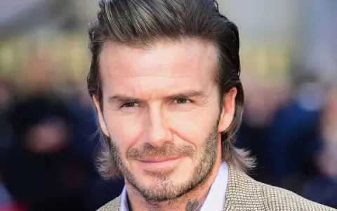Hombre con pelo semi largo hombre liso, barba cuidada y traje a cuadros.