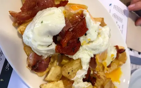 Un plato de patatas fritas con huevos escalfados y jamón, típico de los furanchos de Pontevedra.