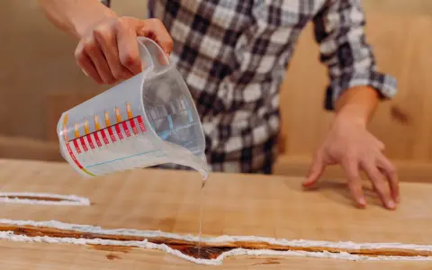Application d'une résine transparente sur un meuble bois gonflé par l'eau, pour le restaurer et le protéger.