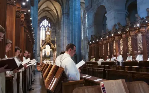 Men in white robes read from books in a grand cathedral, likely participating in matins, a morning prayer service.