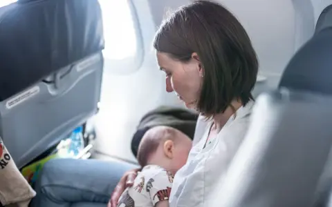 Mamma allatta il suo neonato di 6 mesi in aereo, un momento intimo durante il viaggio.