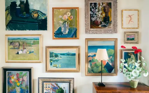 A gallery wall showcasing a diverse collection of paintings, proving that collecting art on a budget can create a vibrant and personal space.