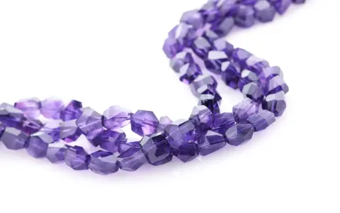 Tre fili di sfaccettate pietre viola, il cui nome è ametista, su sfondo bianco.