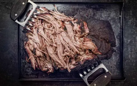 Zartes pulled beef, frisch aus dem Dutch Oven, wird mit Fleischkrallen zerteilt. Perfekt für BBQ!