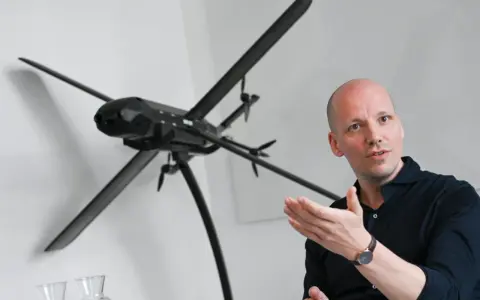 Mann erklärt ein Modell von lba drohnen, das auf einem Stativ steht.