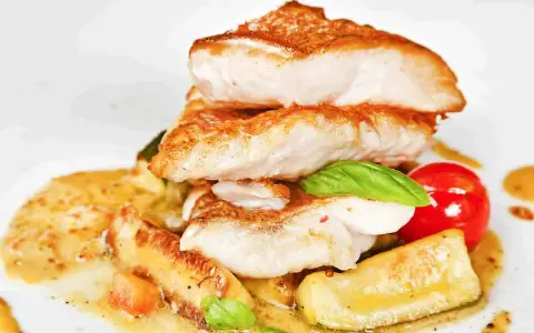 Piatto di pesce impanato e fritto, servito con verdure e salsa. Un'ottima scelta per il tuo menu di pesce.