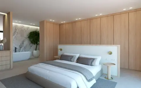 Elegante dormitorio con armarios de madera clara y detalles blancos. La cama, con ropa de cama blanca y cojines grises, se combina perfectamente con la pared de mármol y la bañera.