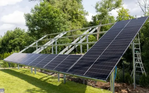 Instalacja fotowoltaiki na gruncie w ogrodzie. Panele słoneczne montowane na metalowej konstrukcji, gotowe do produkcji czystej energii.