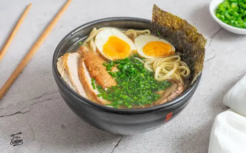 Un delicioso tazón de ramen con fideos, huevo cocido, carne de cerdo, cebollín y alga nori. Una tentadora receta ramen lista para disfrutar.
