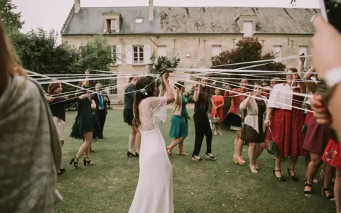 Novia con ramo de flores, rodeada de mujeres con cintas blancas, en el momento cuando se tira el ramo de novia.