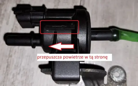 Zawór podciśnienia, potencjalna przyczyna błędu DTC P0170 w Volkswagen. Strzałka wskazuje kierunek przepływu powietrza.