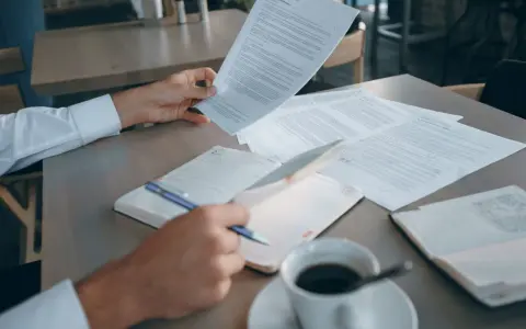 Mężczyzna analizuje dokumenty, szukając informacji o e-sądzie i nakazie zapłaty. Co dalej? Kawa i notatnik czekają.