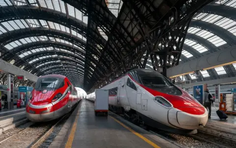 Dwa nowoczesne pociągi, w tym najszybszy pociąg w Europie, stoją na peronie pod imponującą, metalową konstrukcją dachu dworca.