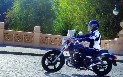 Motocyklista na Kymco Zing 125, zgrabnie pokonujący brukowaną ulicę. Dane techniczne tego modelu pozwalają na komfortową jazdę.