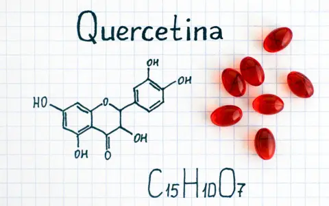 Fórmula química de la quercetina, un flavonoide con propiedades antioxidantes, junto a cápsulas rojas.
