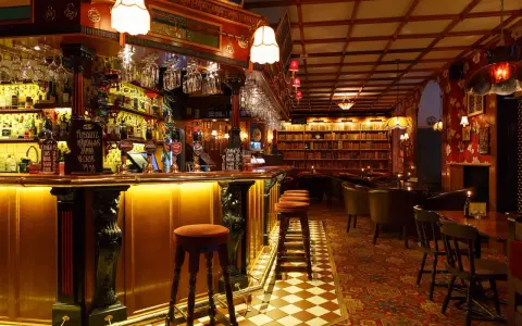 Mysig bar med bokhyllor och bekväma sittplatser, perfekt för att upptäcka Stockholms bästa barer.