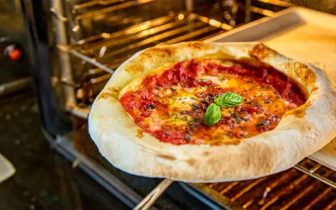 Frisch gebackene Pizza Margherita ohne Backpapier auf einem Ofenrost, mit geschmolzenem Käse und frischem Basilikum.