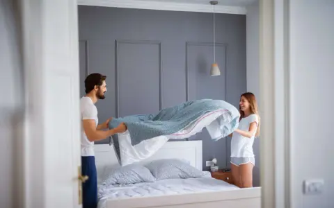 Coppia felice cambia le lenzuola, un promemoria su ogni quanto cambiare le lenzuola per un sonno fresco e igienico.
