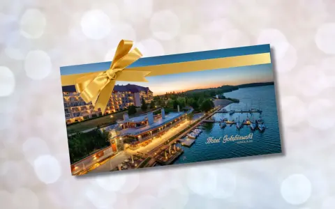 Złota karta Gołębiewski jak otrzymać? Voucher na pobyt w Hotelu Gołębiewski Mikołajki, ozdobiony złotą wstążką.