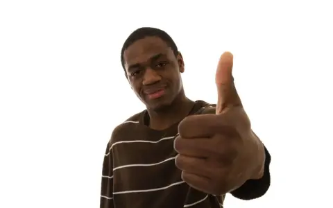 Un jeune homme souriant fait un pouce levé, signe qu'il n'y a pas de souci.
