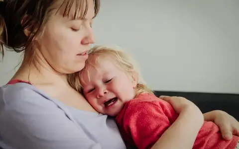 Mama tuli 2-latka, który płacze, przytula go mocno.