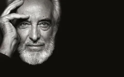 Ritratto in bianco e nero di un uomo anziano con barba bianca, mano sulla fronte. Un fotografo napoletano famoso cattura uno sguardo intenso.