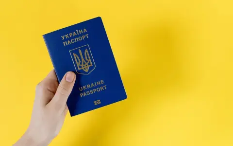 Dłoń trzyma niebieski paszport Ukrainy. Ważność dokumentu jest kluczowa dla statusu ukr do kiedy.
