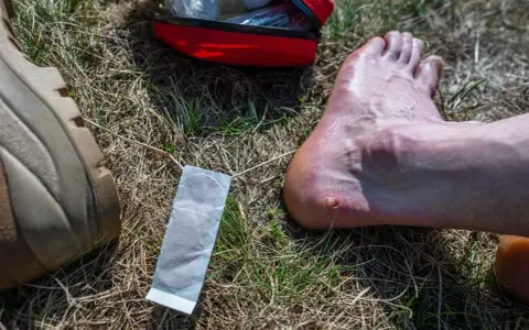 Un pansement à portée de main pour éviter les ampoules au pied. Une trousse de premiers secours rouge est visible.