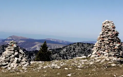 Deux cairns de cailloux marquent le paysage montagneux, offrant des repères visuels sur le sentier.