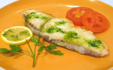 Marrajo a la plancha con perejil y limón, acompañado de rodajas de tomate fresco.