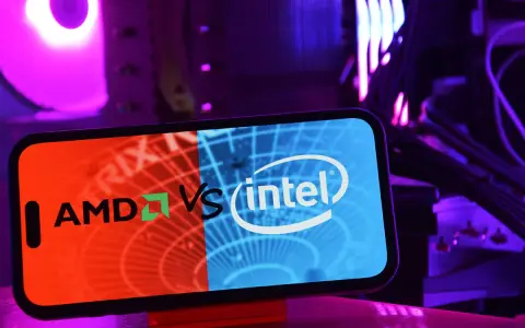 Telefon z logo AMD vs Intel na tle podświetlanego komputera.