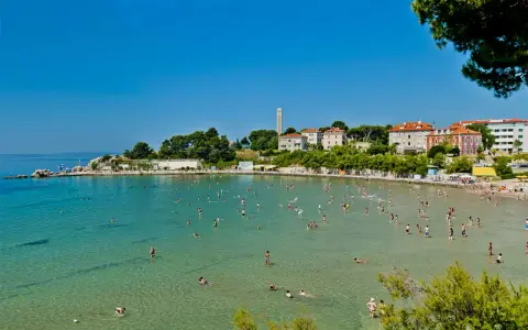 Una giornata di sole sulle spiagge Croazia, con gente che nuota e si rilassa nell'acqua cristallina.