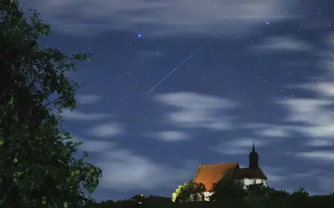 Ein Sternschnuppenregen über einer kleinen Kirche. Man sieht, wann sieht man sternschnuppen, wenn der Himmel klar ist und die Nacht dunkel.