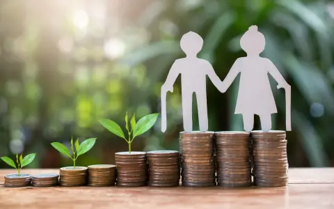 Figuras de papel de ancianos sobre pilas de monedas y brotes verdes. ¿Es sostenible el sistema de pensiones en España?