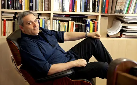 L'autore, circondato da libri, si rilassa su una poltrona. Tra i titoli, si intravede un riferimento a de Giovanni ultimo libro.