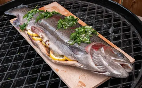 Lachsforelle auf einem Holzbrett, gefüllt mit Zitrone und Kräutern, bereit für den Grill. Die Kerntemperatur ist entscheidend für perfekten Fisch.
