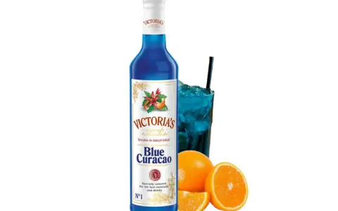 Niebieski syrop Blue Curacao Victoria's, idealny do drinków z Malibu i orzeźwiających koktajli. Obok szklanka z lodem i napojem.